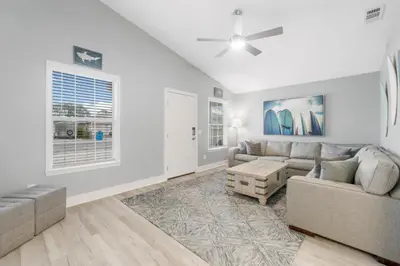 a living room with a couch and a table at Blue & Red Neptune by Nautical Properties Vacation Rentals in Panama City Beach