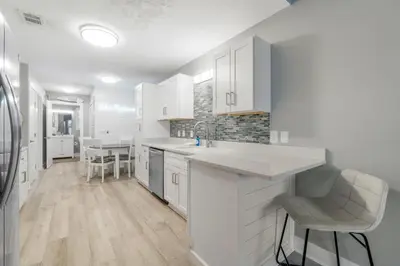 a kitchen with white cabinets and a table with chairs at Blue & Red Neptune by Nautical Properties Vacation Rentals in Panama City Beach