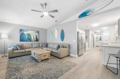a living room with a couch and a table at Blue & Red Neptune by Nautical Properties Vacation Rentals in Panama City Beach