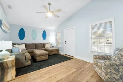 a living room with a couch and a ceiling fan at Blue & Red Neptune by Nautical Properties Vacation Rentals in Panama City Beach