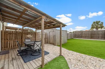 a wooden deck with a table and a pergola at Blue & Red Neptune by Nautical Properties Vacation Rentals in Panama City Beach