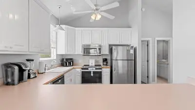 a kitchen with white cabinets and a stainless steel refrigerator at Walk to Santa Rosa Beach Private Pool Balcony and Coastal Views in Santa Rosa Beach