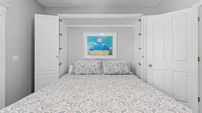 a white bedroom with a bed with blue pillows at Walk to Santa Rosa Beach Private Pool Balcony and Coastal Views in Santa Rosa Beach