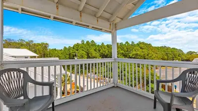 a balcony with two chairs and a view of trees at Walk to Santa Rosa Beach Private Pool Balcony and Coastal Views in Santa Rosa Beach
