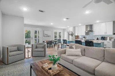 a living room with a couch and chairs and a kitchen at Beach & Bubbles in Santa Rosa Beach