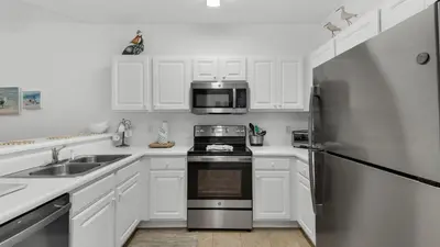 a kitchen with white cabinets and a stainless steel refrigerator at Heron's Watch 6207 in Santa Rosa Beach