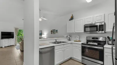 a kitchen with white cabinets and a sink and microwave at Heron's Watch 6207 in Santa Rosa Beach