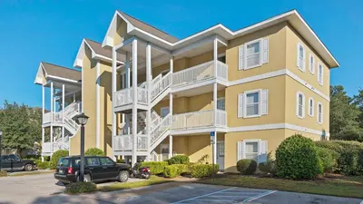 a yellow apartment building with white balconies at Heron's Watch 6207 in Santa Rosa Beach