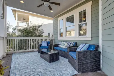 a porch with two wicker chairs and a table at Gram's Beach Spot in Santa Rosa Beach