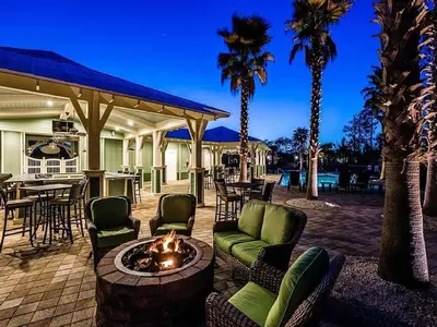 a patio with chairs and a fire pit with palm trees at Gram's Beach Spot in Santa Rosa Beach