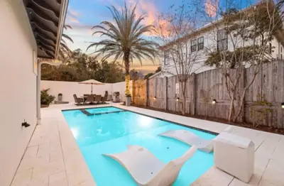 a swimming pool with two white chairs in front of a house at Saltaire-2 in Santa Rosa Beach