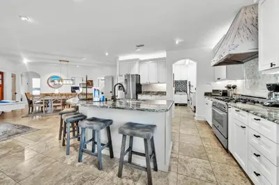 a kitchen with white cabinets and a island with bar stools at Saltaire in Santa Rosa Beach