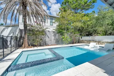 a swimming pool with a palm tree and a house at Saltaire in Santa Rosa Beach