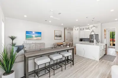 a kitchen and living room with white walls and a large island at Above It All in Inlet Beach