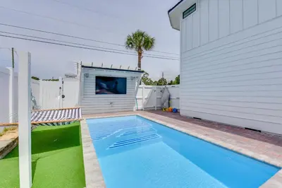 a swimming pool is next to a white house at Walk to Laguna Beach PCB Home with Pool Near Gulf! in Panama City Beach