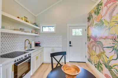 a kitchen with white cabinets and a colorful wallpaper at Walk to Laguna Beach Modern Studio in PCB! in Panama City Beach
