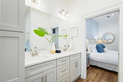 a bathroom with two sinks and a mirror and a bed at 30A Seacrest Beach Access PoolGolf CartBikes in Inlet Beach