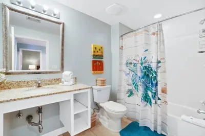 a bathroom with a toilet and a sink and a mirror at Oceanfront Penthouse CornerUnit 1950sf with beach service in Panama City Beach