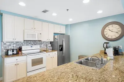 a kitchen with white cabinets and a clock on the wall at Oceanfront Penthouse CornerUnit 1950sf with beach service in Panama City Beach