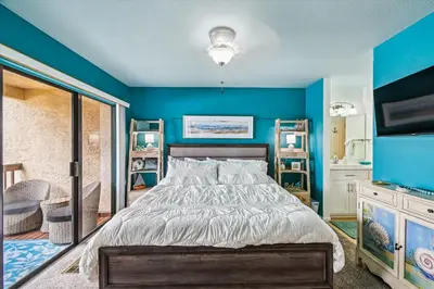 a bedroom with a bed and a blue wall at Beachwalk 17B home in Panama City Beach