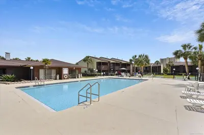a swimming pool with chairs in a resort at Beachwalk 17B home in Panama City Beach