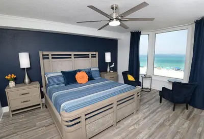 a bedroom with a bed with blue walls and the ocean at Emerald Beach 325 in Panama City Beach