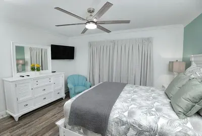 a bedroom with a bed and a dresser and a ceiling fan at Emerald Beach 325 in Panama City Beach
