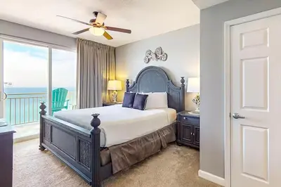 a bedroom with a bed and a balcony with the ocean at Sterling Reef 902 in Panama City Beach