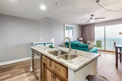 a kitchen with a sink and a living room at Sterling Reef 902 in Panama City Beach