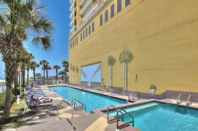 a swimming pool with palm trees and a building at Sterling Reef 902 in Panama City Beach