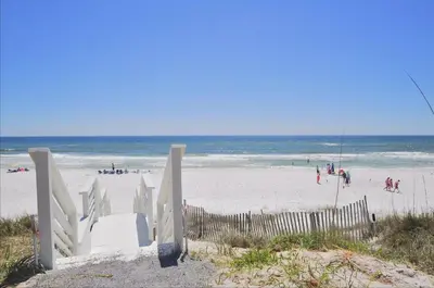 a sandy beach with a fence and people on the beach at Sea Echo + Ocean Park in Santa Rosa Beach