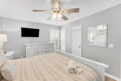 a white bedroom with a bed and a ceiling fan at Grey Zen in Panama City Beach