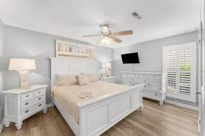 a white bedroom with a bed and a ceiling fan at Grey Zen in Panama City Beach