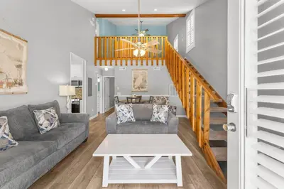 a living room with a couch and a staircase at Grey Zen in Panama City Beach