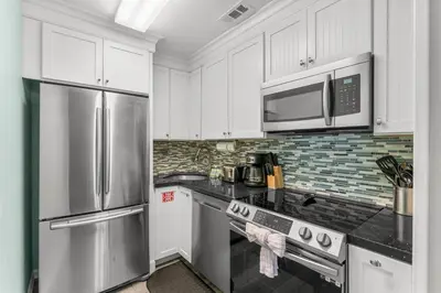 a kitchen with white cabinets and stainless steel appliances at Grey Zen in Panama City Beach
