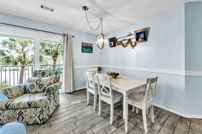 a dining room with a table and chairs and a couch at Beachside Villas 1022 in Santa Rosa Beach
