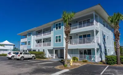 a large apartment building with palm trees in a parking lot at Beachside Villas 1022 in Santa Rosa Beach