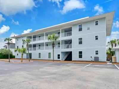 a white building with palm trees in a parking lot at Beachside Villas 1211 in Santa Rosa Beach