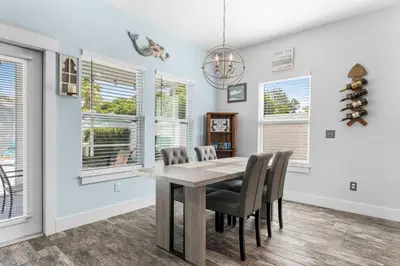 a dining room with a table and chairs and windows at Beach House - Lazee Daze by Panhandle Getaways in Panama City Beach