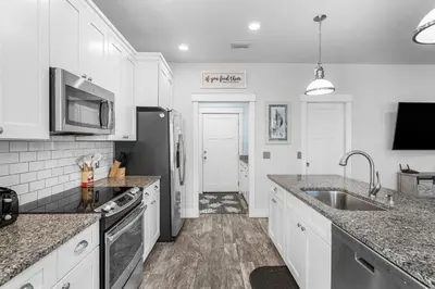 a kitchen with white cabinets and a stainless steel refrigerator at Beach House - Lazee Daze by Panhandle Getaways in Panama City Beach
