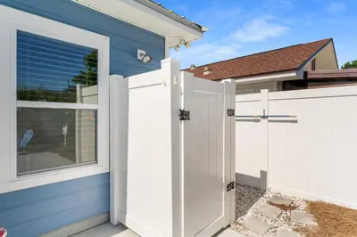 a white garage door and a blue house at Beach House - Lazee Daze by Panhandle Getaways in Panama City Beach