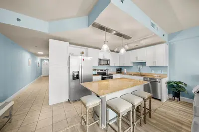 a kitchen with white cabinets and a island with bar stools at Laketown Wharf #0703 in Panama City Beach
