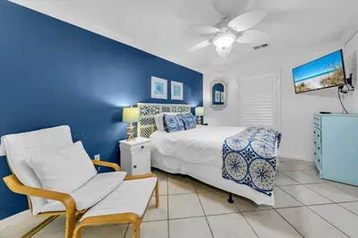 a blue bedroom with a bed and a chair at Beachside Villas 412 in Santa Rosa Beach
