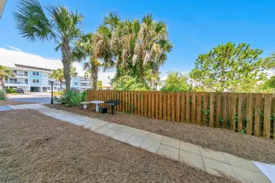 a wooden fence with a bench and palm trees at Beachside Villas 412 in Santa Rosa Beach