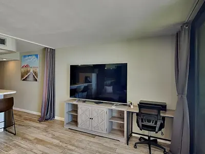a living room with a television and a desk with a chair at Edgewater Tower III #709 in Panama City Beach