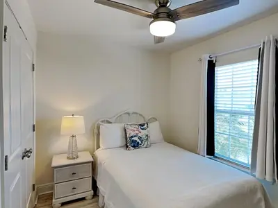 a bedroom with a bed with a ceiling fan and a window at The Pink Flamingo in Rosemary Beach