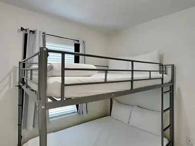 two bunk beds in a room with a window at The Pink Flamingo in Rosemary Beach