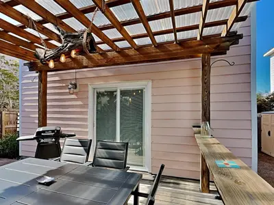 a patio with a table and chairs and a pergola at The Pink Flamingo in Rosemary Beach