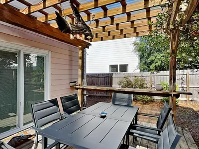 a table and chairs on a patio with a pergola at The Pink Flamingo in Rosemary Beach