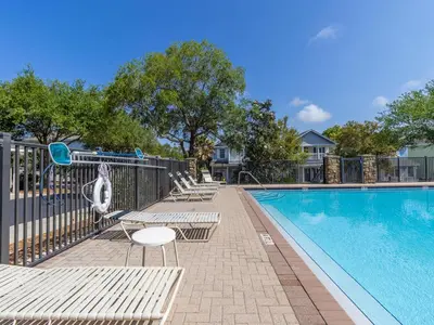 a swimming pool with chairs and a swing at The Pink Flamingo in Rosemary Beach